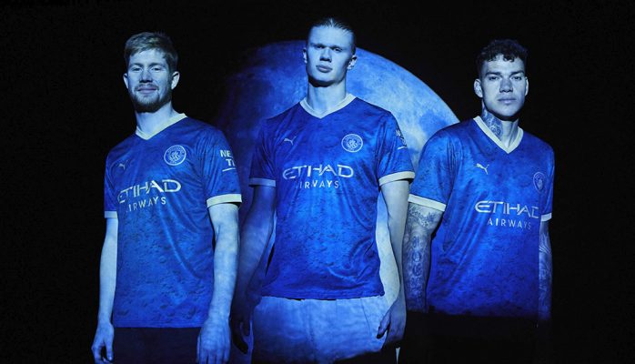 Ba siêu sao cầu thủ bóng đá của Manchester City đứng ngang hàng mặc áo bóng đá màu xanh đen với logo màu vàng đồng họa tiết mừng tết âm lịch văn hóa á đông